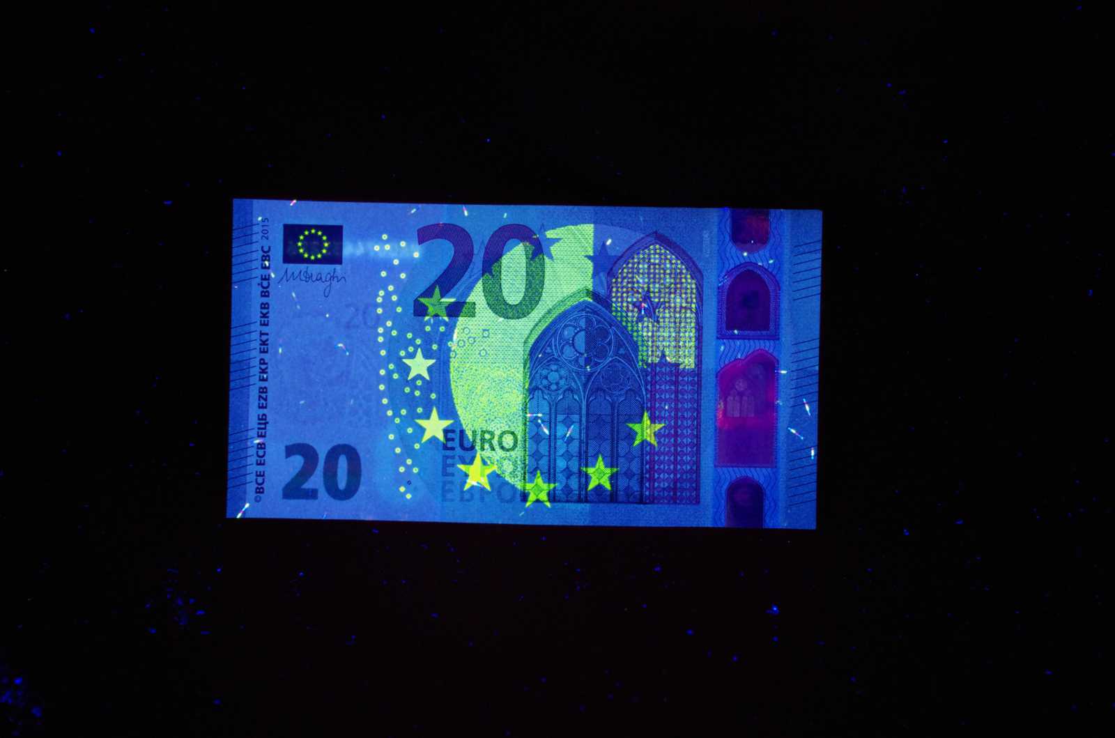 Unter einer UV-Lampe leuchten winzige Pigmente unserer Geldscheine in den verschiedensten „Europium“-Farben. (Foto: FH Münster/Patrick Pues)