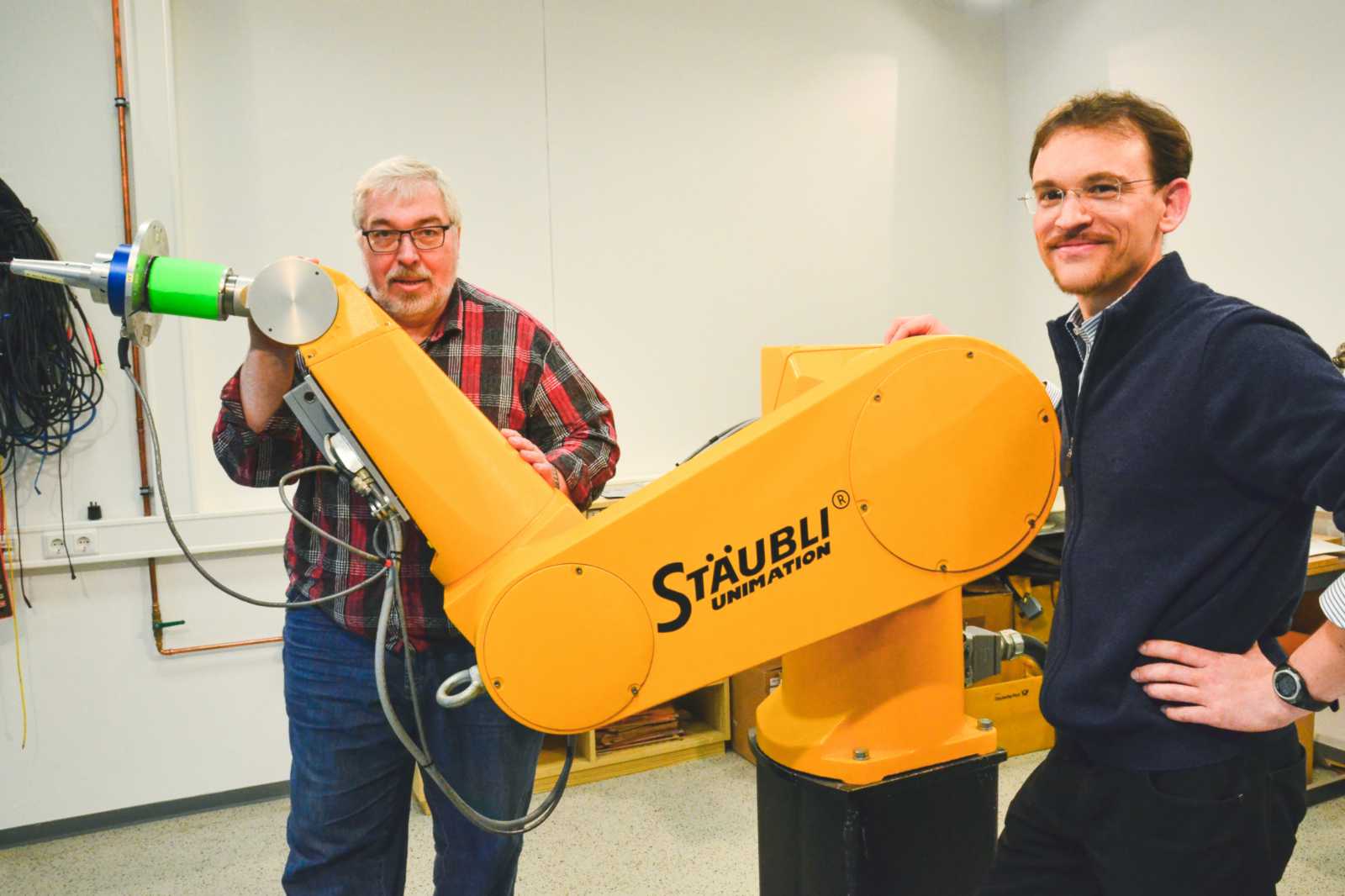 Prof. Dr. Uwe Mohr (l.) und Prof. Dr. Falk Salewski arbeiten unter anderem mit Roboterarmen wie diesem hier, der an der FH Münster am Fachbereich Elektrotechnik und Informatik zum Einsatz kommt. (Foto: FH Münster/Pressestelle)