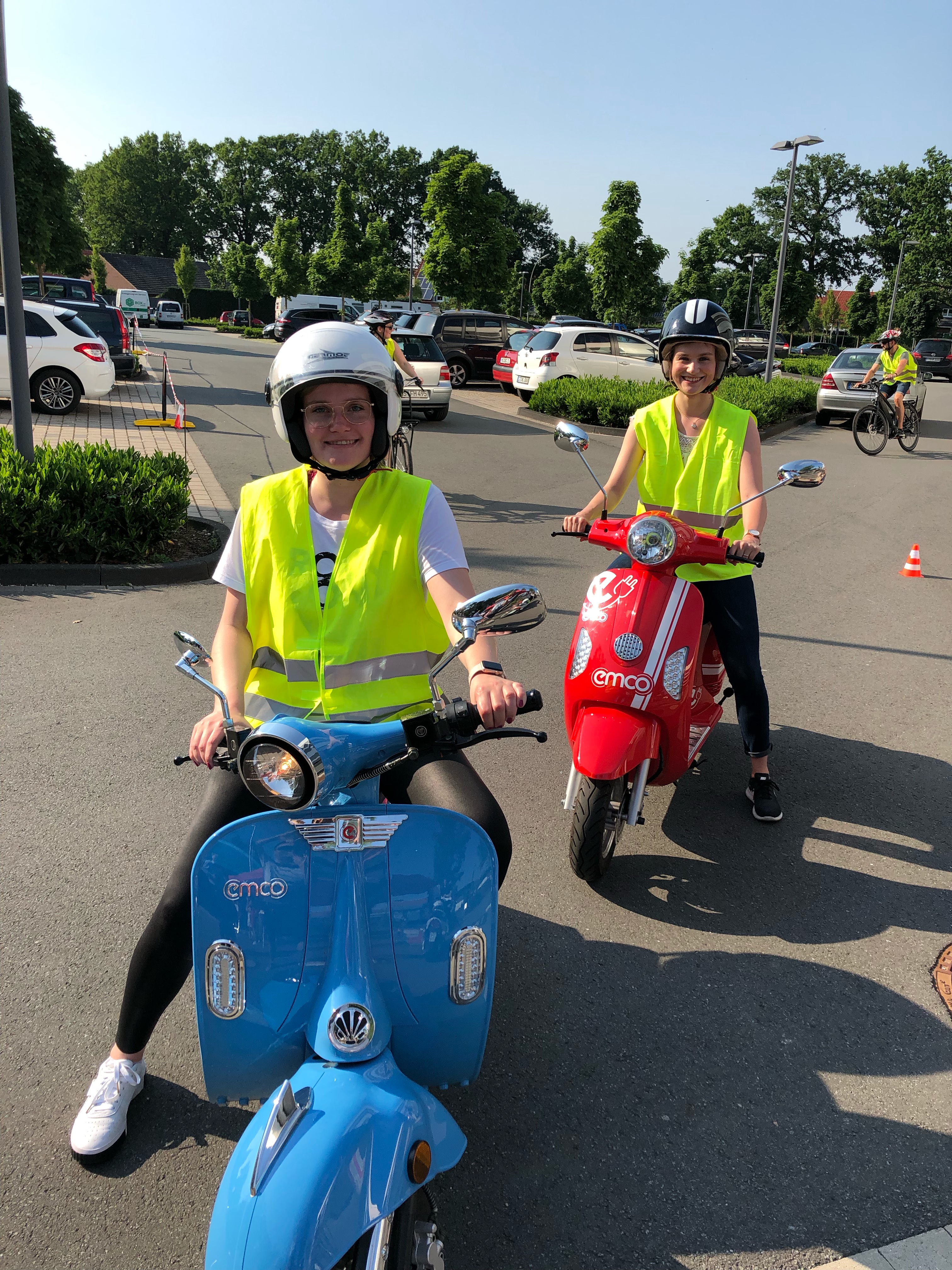 Zwei Personen mit einem blauen und einem roten E-Motorroller.